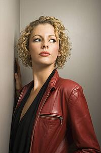 Young adult woman wearing red jacket leaning on wall