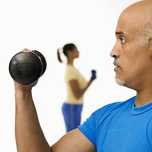 Man exercising using dumbbells with woman in background