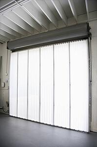 Interior of warehouse building with large window and vertical blinds.