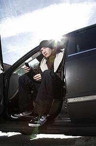 Male teenager sitting in car holding his cell phone.