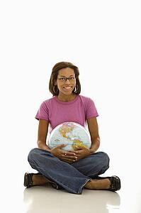 Woman sitting on floor holding globe and smiling at viewer