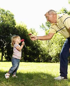 Grandfather and granddaughter holding flowers and smelling