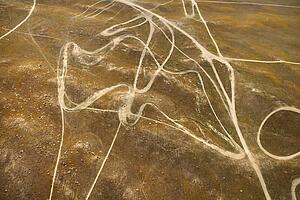 Aerial of barren landscape with dirt road trails in California, USA