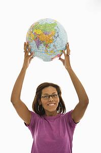 Woman holding globe over head and smiling at viewer