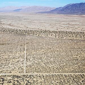 Aerial view of remote California desert with grid pattern and mountain range in background.