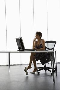 Caucasian businesswoman sitting at desk with computer in office.
