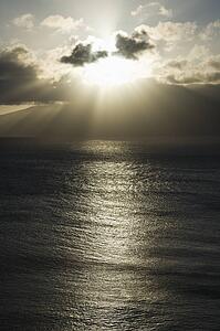 Pacific ocean and island with sun streaming through clouds