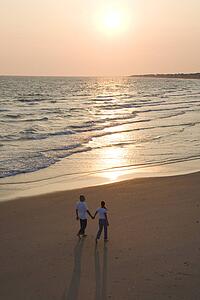 Aerial of couple holding hands and walking on beach on Bald Head Island, North Carolina