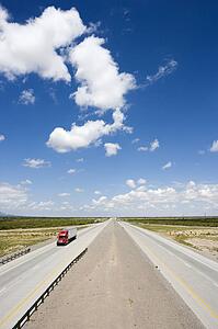 High angle view of highway with tractor trailer truck and blue cloudy sky.