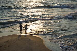 Aerial view of couple holding hands on beach in Bald Head Island, North Carolina at sunset