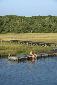Aerial view of two teenage boys fishing from dock in marshy lowlands of Bald Head Island, North Carolina.