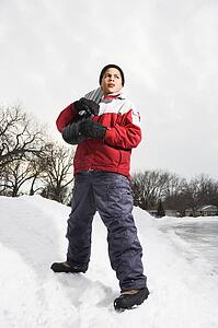 Boy standing holding snowboard in snow.