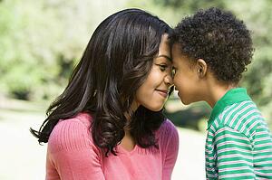 Mother and young son with heads together smiling.