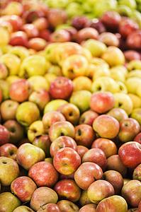 Red and yellow apples piled on table at produce market.