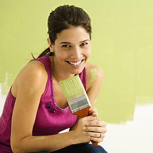 Woman kneeling in front of partially painted wall