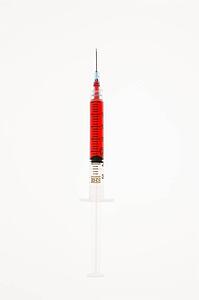 Hypodermic needle filled with red liquid on white background.