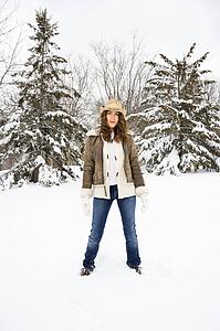Caucasian young adult female standing in snow wearing straw cowboy hat.