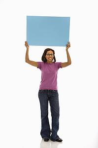Woman holding sign over head smiling at viewer