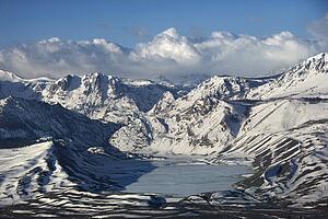 Aerial of snowy mountain landscape with frozen lake in Inyo National Forest, California, USA