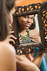 Woman smiling at reflection in mirror wearing necklace