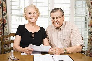 Mature Caucasian couple looking at their bills.