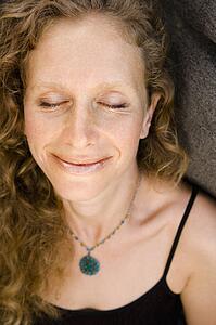 Caucasian mid-adult woman smiling with eyes closed.