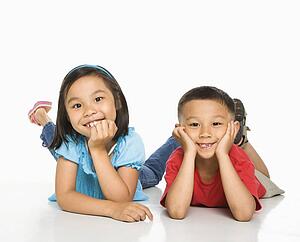 Young brother and sister lying on floor with head on hands