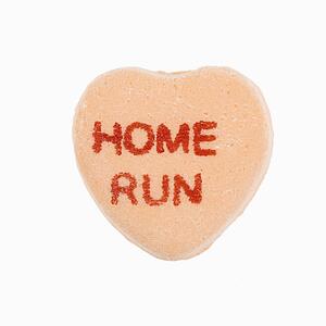 Orange candy heart that reads home run against white background.