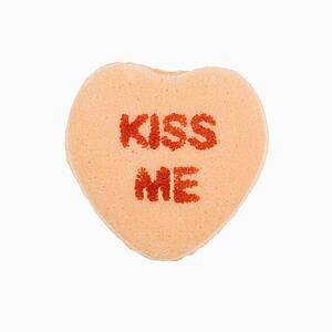 Orange candy heart that reads kiss me against white background.