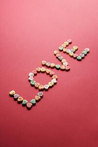 Colorful candy hearts with sayings on them arranged to spell the word love.