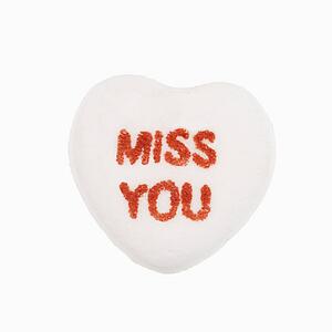 White candy heart that reads miss you against white background.