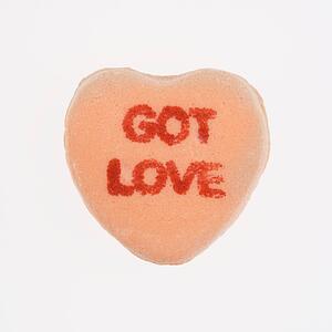 Orange candy heart that reads got love against white background.