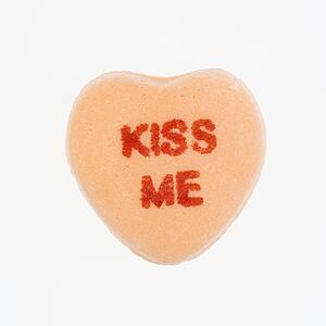 Orange candy heart that reads kiss me against white background.