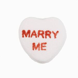 White candy heart that reads marry me against white background.