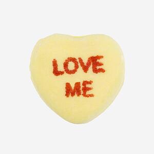 Yellow candy heart that reads love me against white background.