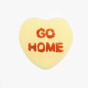 Yellow candy heart that reads go home against white background.