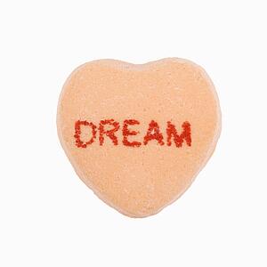 Orange candy heart that reads dream against white background.