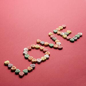 Colorful candy hearts with sayings on them arranged to spell the word love.