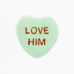 Green candy heart that reads love him against white background.