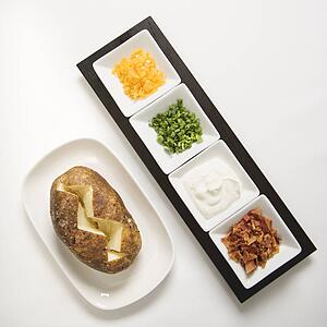 Baked potato sliced down the middle with several toppings.