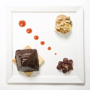 Chocolate cheesecake pyramid with dried cherries and pistachio praline.