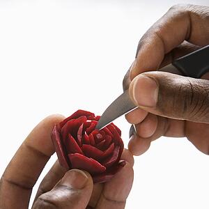 African-American male hands carving a red beet into a rose.