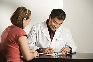 Asian American male doctor consulting with Caucasian female patient.