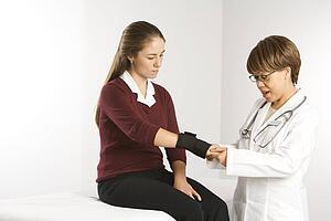 African American middle-aged female doctor examining wrist of Caucasian mid-adult female patient.