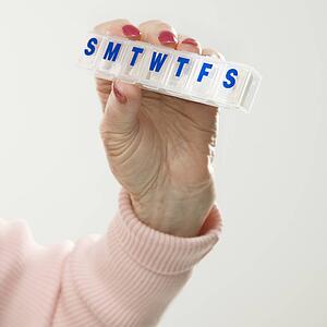 Caucasian senior female hand holding pill box.