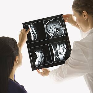 Caucasian and Asian Chinese mid-adult female doctors analyzing x-ray. 