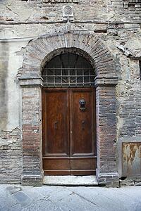 Wooden door with brick archway, Italy.