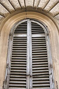 Close-up of wooden shutters and arched window in Rome, Italy.