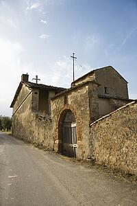 Old stone buillding in state of disrepair with arched gated entrance in Tuscany. 
