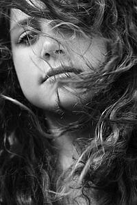 Young adult female with hair blowing in face looking at viewer
